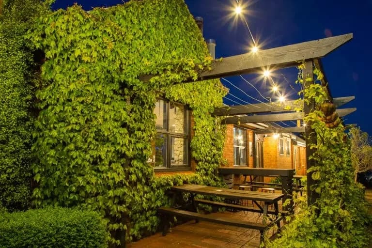 The lit verandah and pergola of the hotel at dusk